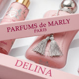 Elegant woman holding a luxurious Delina De Marly Box perfume set, featuring elegant packaging and floral design.