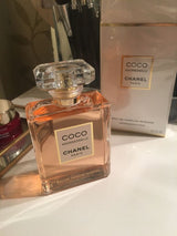 Chanel Coco Mademoiselle perfume for women, elegant glass bottle with floral and citrus fragrance, on a neutral background